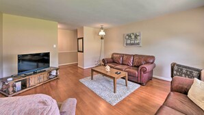 A living room with a TV on a wooden stand, a leather sofa, a coffee table, and a lamp. - Cozy Charlotte Retreat w/ Yard ~ 5 Mi to Dtwn (Charlotte)