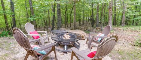 A circular outdoor seating area with four Adirondack chairs, a fire pit, and a gravel ground.