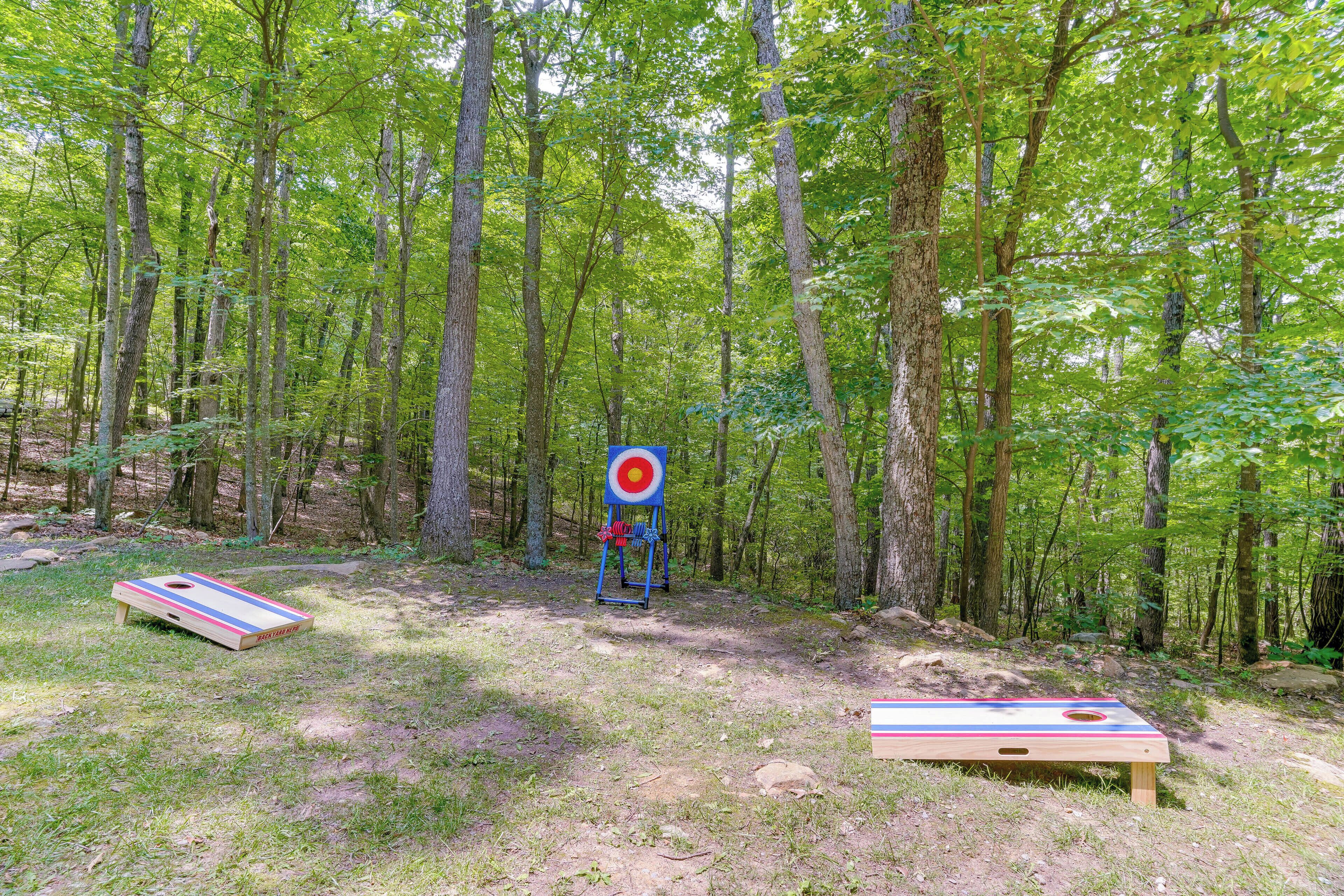 A forested area with a target and two shuffleboard tables.
