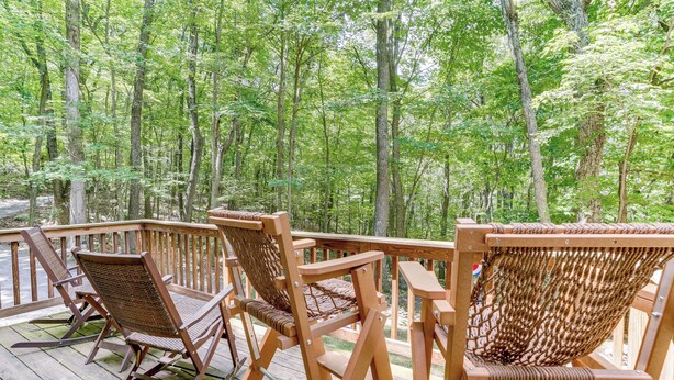 A wooden deck with wicker rocking chairs and a hammock overlooking a forest. - Cabin w/ Deck & Screened-in Porch in New Market! (New Market)
