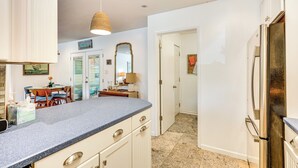 Eine Küche mit einer Granit Arbeitsplatte, weißen Schränken und einem Edelstahl-Kühlschrank.