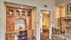 A kitchen with wooden cabinets, a granite countertop, and a dining area with a chair and a table. - Steps to Ski Resort: Sugar Mountain Condo! (Banner Elk)