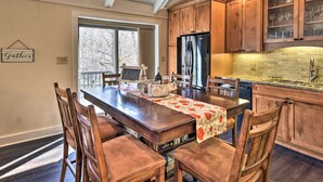 A kitchen with wooden cabinets, a stainless steel refrigerator, and a dining table with chairs. - Steps to Ski Resort: Sugar Mountain Condo! (Banner Elk)