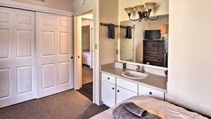 A bedroom with a bed, a bathroom with a sink and mirror, and a closet with white doors. - Steps to Ski Resort: Sugar Mountain Condo! (Banner Elk)