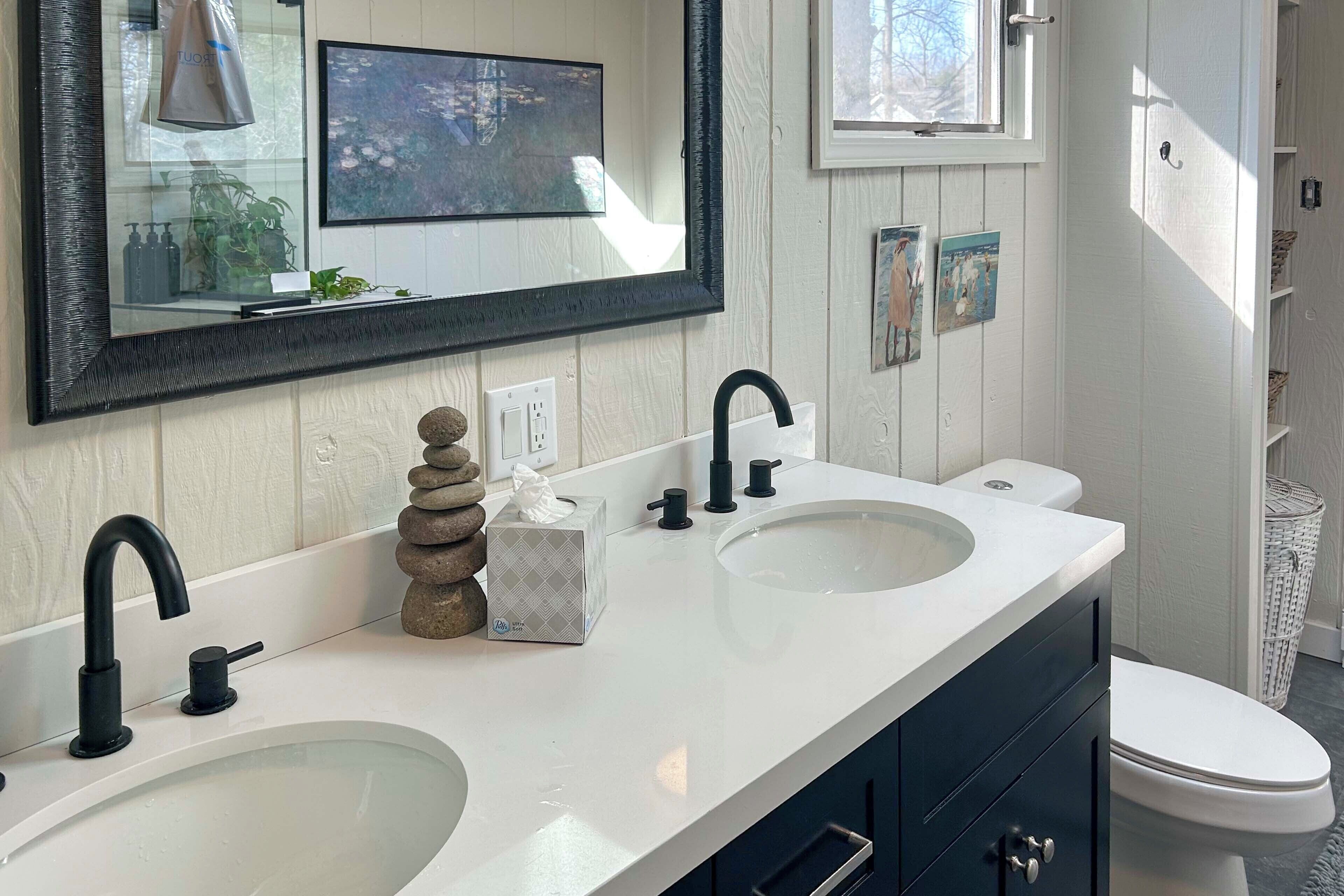 A bathroom with two sinks, a large mirror, and a toilet.