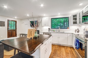 A modern kitchen with white cabinets, a wooden countertop, and a large window with a forest view. - Sawyer Retreat w/ Fire Pit < 2 Mi to Beaches! (Harbert)