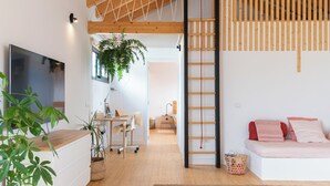 Ein modernes Interieur mit freiliegenden Holzbalken, einer Treppe, einem Sofa und einem Fernseher.