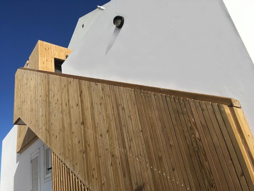 Un edificio moderno con fachada de madera y sección superior blanca.