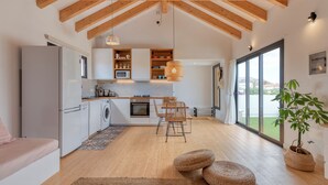 Eine moderne Küche mit Holzbalken, einem Essbereich mit Tisch und Stühlen sowie einem großen Fenster mit Aussicht.
