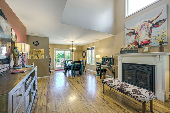 A spacious living room with hardwood floors, a fireplace, a dining area with chairs, and a large painting on the wall. - Hike, Ski & Dine: Pagosa Springs Getaway! (Pagosa Springs)