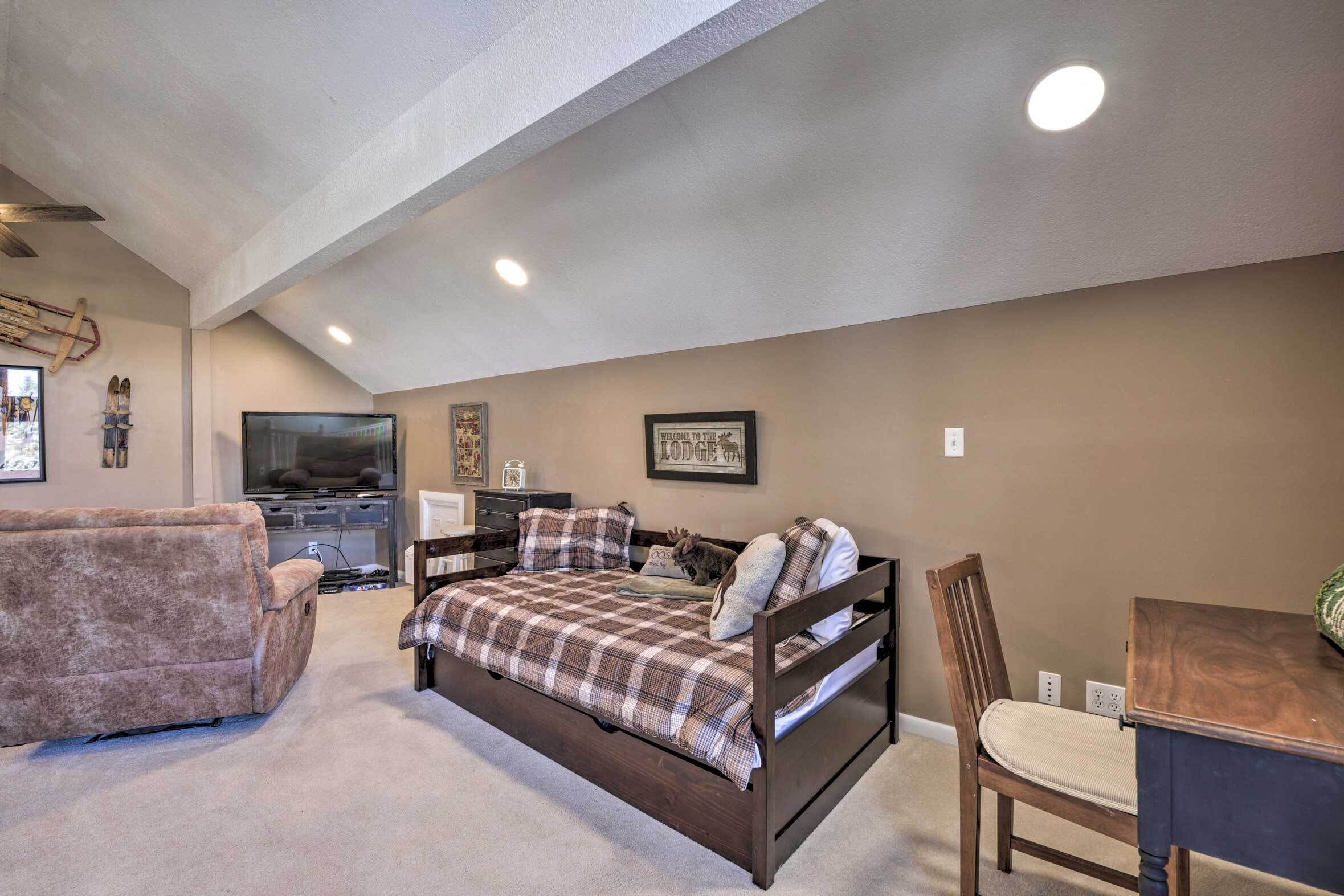 A bedroom with a bed, a chair, a television, and a desk.