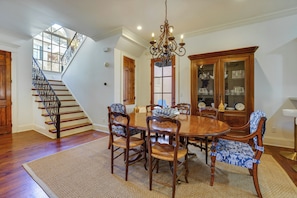 A dining room with a wooden table, chairs, and a chandelier. There is a staircase with a railing leading to another room. - Large, Elegant Home < 2 Miles to Ole Miss! (Oxford)