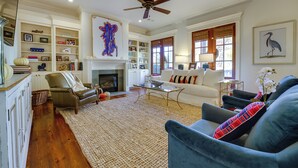 A spacious living room with a fireplace, a ceiling fan, and a bookshelf filled with books and decorative items. - Hector's Hotty Toddy: 2 Mi to Ole Miss (Oxford)
