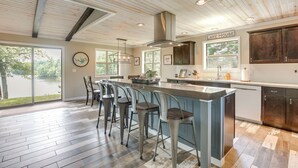 A modern kitchen with a large island, bar stools, and a view of a lake. - Tranquil Lakefront Cabin: Fire Pit, Grill & Patio (Tomahawk)