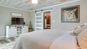 A bedroom with a bed, a television, a painting, and a sliding door. - Tranquil Lakefront Cabin: Fire Pit, Grill & Patio (Tomahawk)
