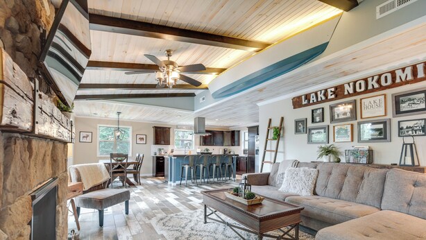 A spacious living room with a fireplace, a large sofa, a coffee table, and a dining area with a bar. - Tranquil Lakefront Cabin: Fire Pit, Grill & Patio (Tomahawk)