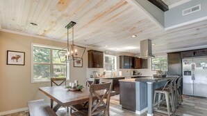A spacious kitchen with a central island, wooden dining table, and bar stools. - Tranquil Lakefront Cabin: Fire Pit, Grill & Patio (Tomahawk)