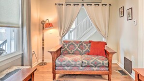 A cozy room with a patterned sofa, a floor lamp, and a window with curtains. - Penn Yan House Rental - Close to Wineries! (Penn Yan)