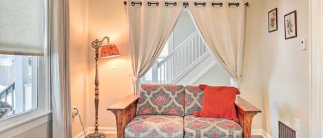 A cozy room with a patterned sofa, a floor lamp, and a window with curtains.