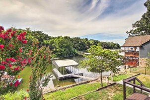 Una propiedad a orillas del río con un muelle, un espacio cubierto y vistas al río y la vegetación circundante.