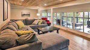 A modern living room with a sectional sofa, a coffee table, and a view of the outdoor patio area. - Dock, Deck & Boat Slip: Lakefront Eucha Home (Eucha)