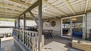 A covered outdoor deck with wooden flooring, a white railing, and a seating area with a table and chairs. - Spacious Family Home w/ Garage Game Room & Office! (Boise)