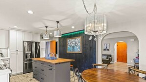 A modern kitchen with a central island, stainless steel appliances, and a dining area with a wooden table and chairs. - Spacious Family Home w/ Garage Game Room & Office! (Boise)