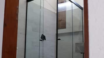 A modern bathroom with a glass-enclosed shower, a white toilet, and a wooden door frame.