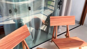 Una habitación moderna con pared de vidrio, un banco de madera y una pequeña mesa.