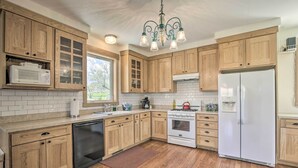 Una cocina con gabinetes de madera, un refrigerador blanco, una estufa y un microondas.