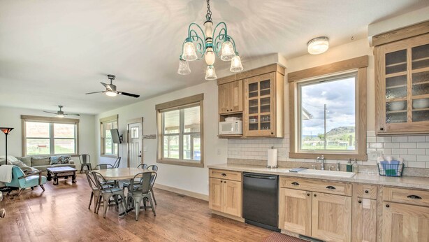 Una cocina amplia con armarios de madera, lavavajillas y comedor con mesa y sillas.