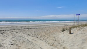 A sandy beach with a wooden post and a blue sign. - Emerald Isle Vacation Home: Walk to Beach! (Emerald Isle)