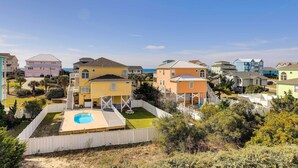 A residential area with colorful houses, a swimming pool, and a white fence. - Emerald Isle Vacation Home: Walk to Beach! (Emerald Isle)