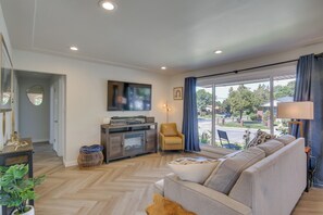 A modern living room with a sofa, TV, and a view of the street. - Denver Vacation Home w/ Home Theater! (Denver)