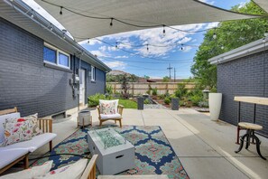 A covered patio area with a seating arrangement, a glass-top table, and a decorative rug. - Denver Vacation Home w/ Home Theater! (Denver)