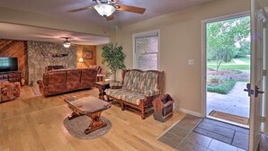 A living room with a stone fireplace, leather sofa, and a television. - Hendersonville Home w/ Fire Pit: 5 Mi to Downtown! (Hendersonville)