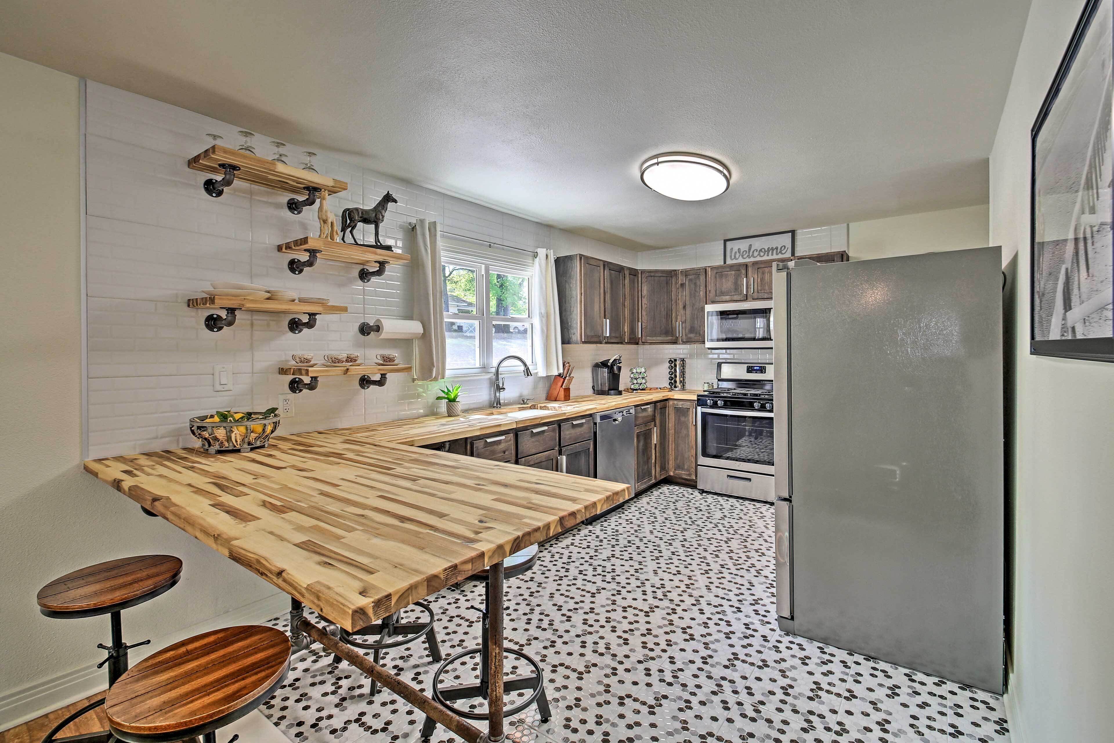 A kitchen with a wooden island, stainless steel appliances, and a patterned floor.