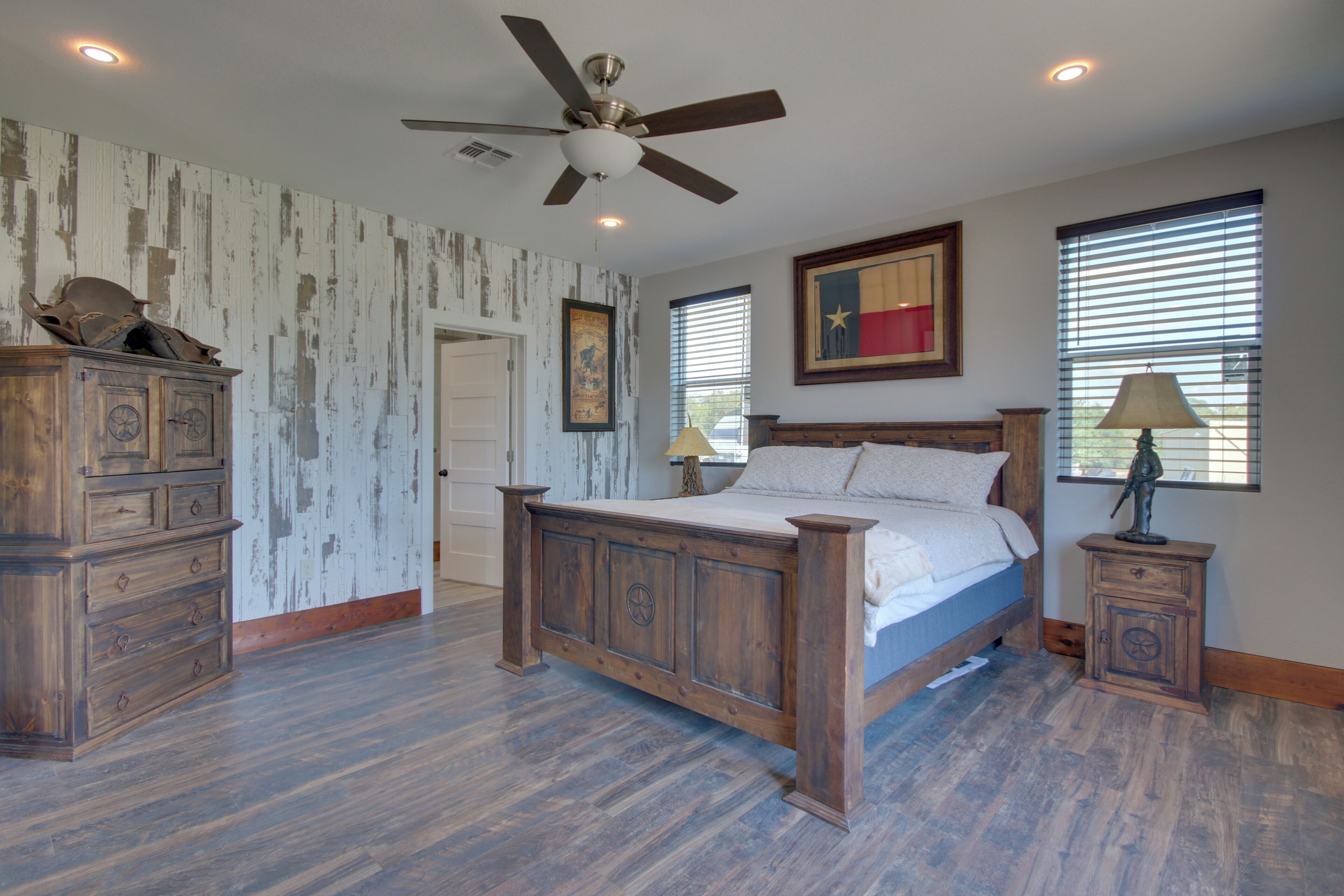 A bedroom with a wooden bed, a ceiling fan, a dresser, and a nightstand.