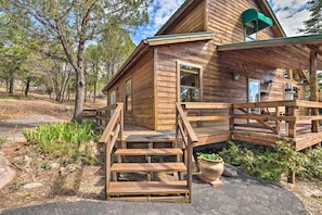 A wooden cabin with a porch and steps leading to the entrance.