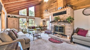 A spacious living room with a fireplace, wooden ceiling, and large windows. - Alto Home w/ Deck & Views ~ 15 Mi to Ski Apache! (Alto)