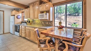 A kitchen with wooden cabinets, a microwave, a refrigerator, and a dining table with chairs. - Alto Home w/ Deck & Views ~ 15 Mi to Ski Apache! (Alto)