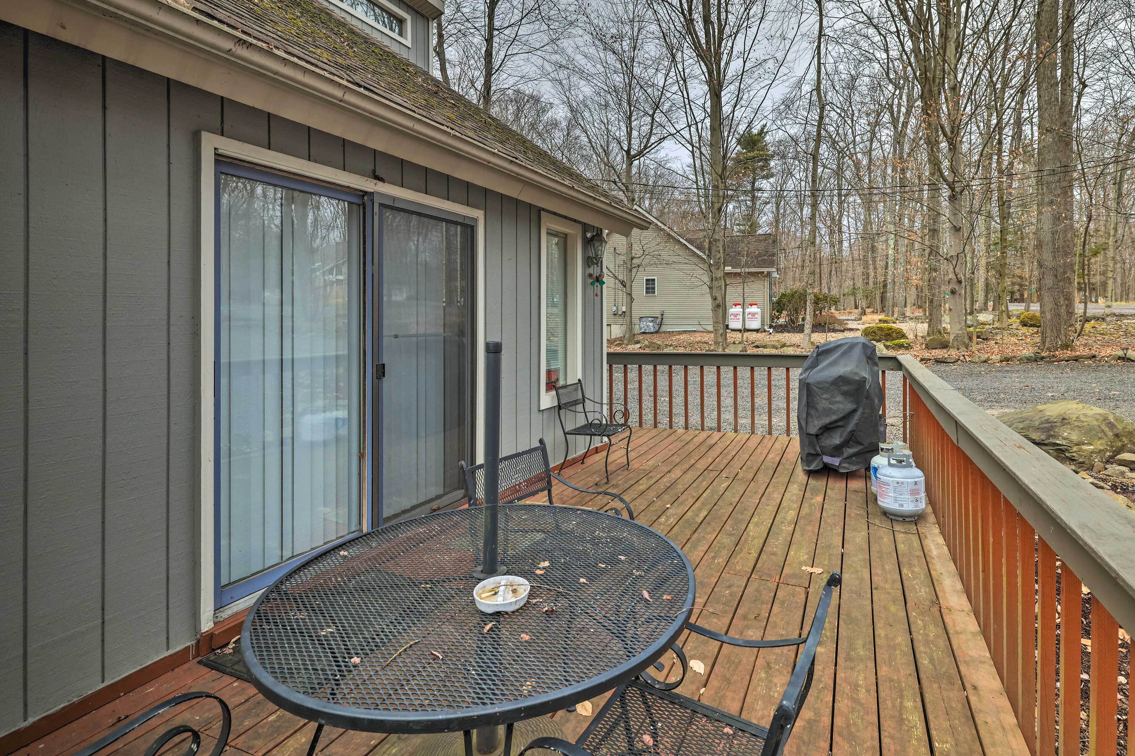 A deck with a table and chairs, a barbecue grill, and a covered grill.