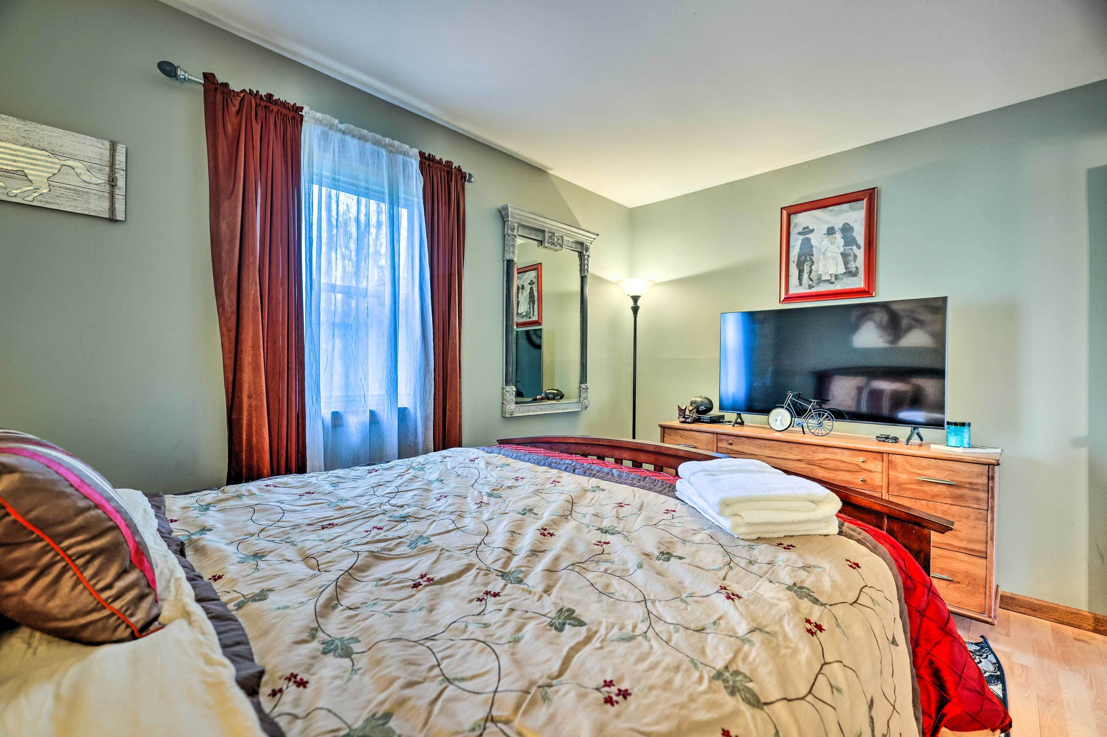 A bedroom with a bed, a dresser, a mirror, a television, and a framed picture on the wall.