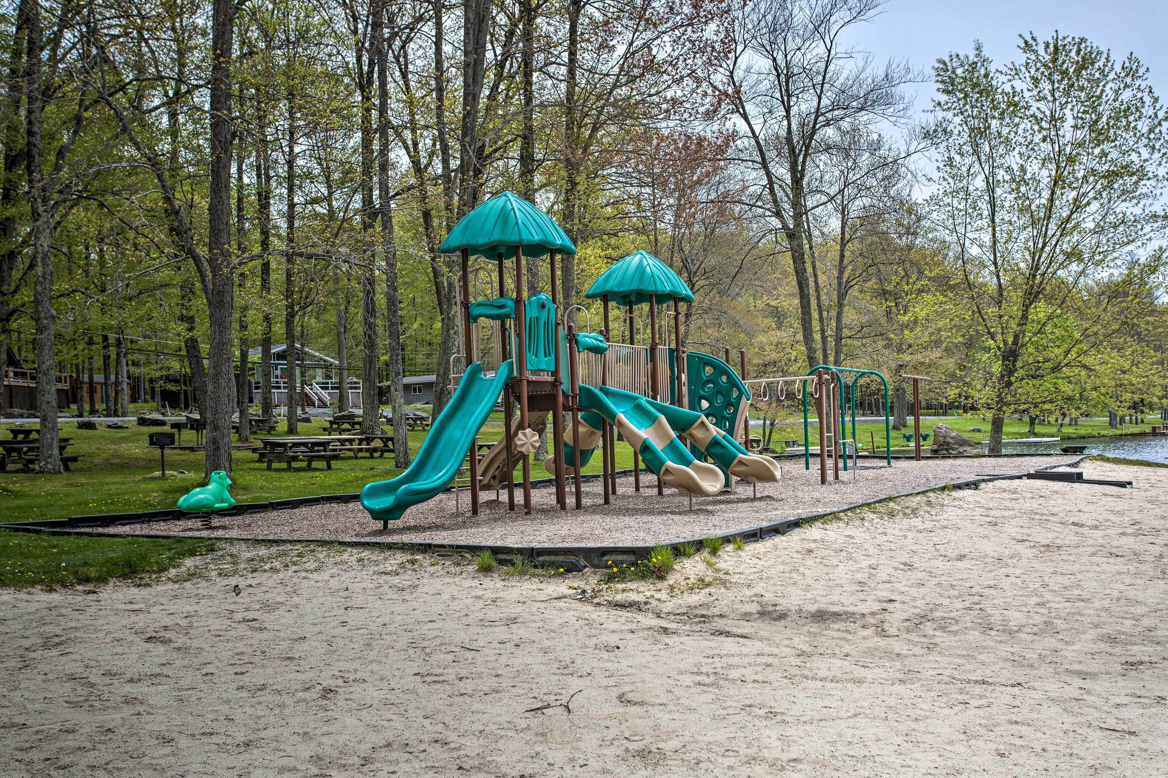 A playground with slides and climbing structures surrounded by trees.