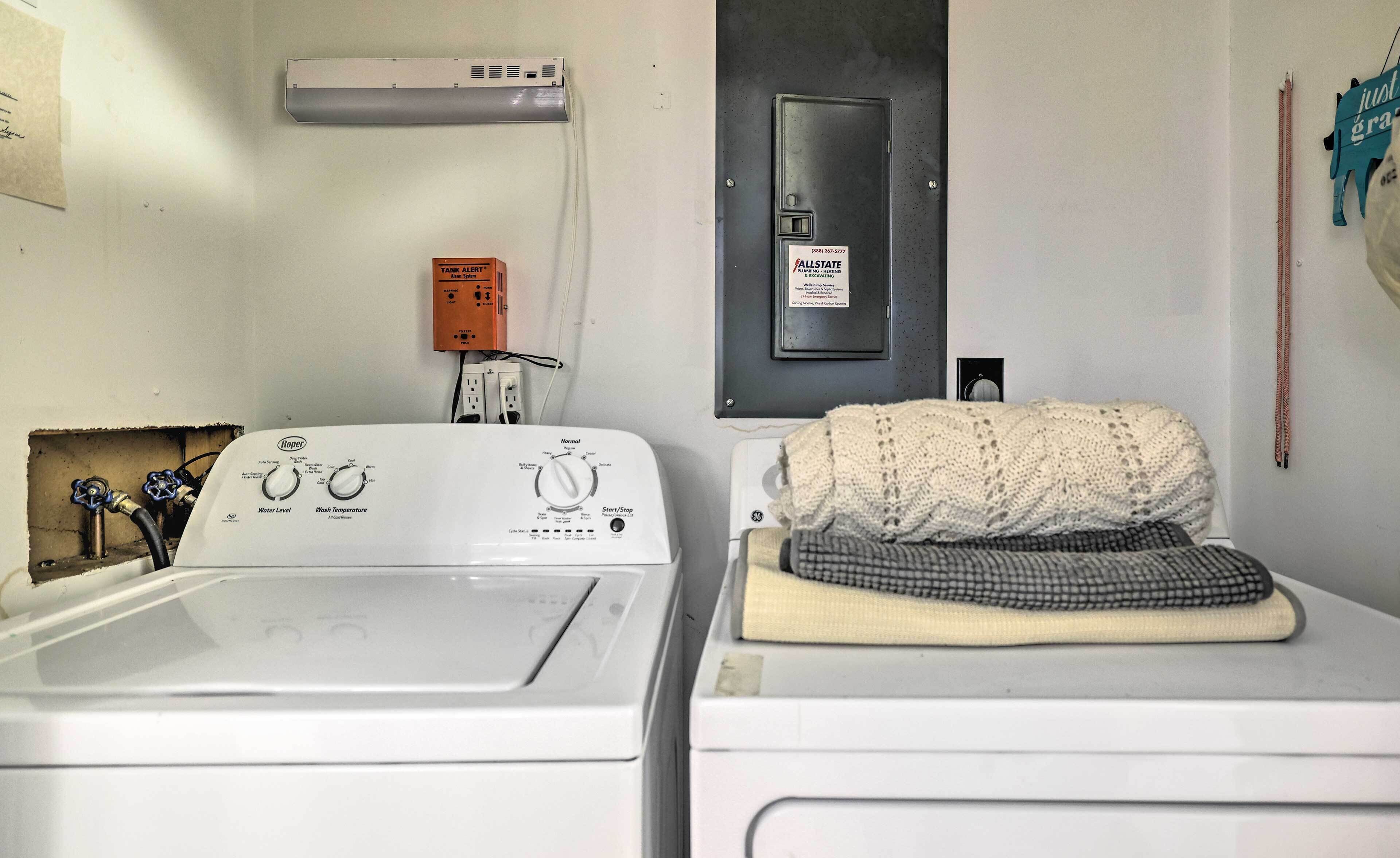 A laundry area with a front-loading washer and dryer, a water heater, and a thermostat.