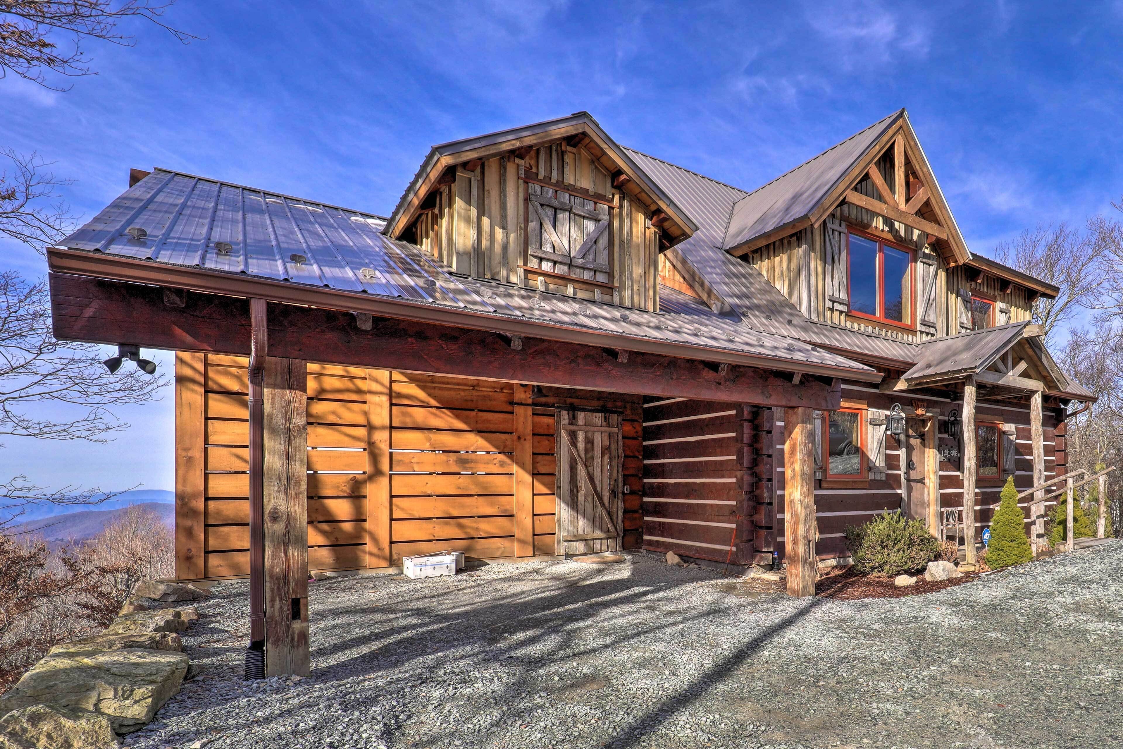 A rustic log cabin with a metal roof, wooden exterior, and a gravel driveway.