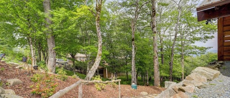 A wooden staircase surrounded by trees and rocks, leading to a building with a metal roof.