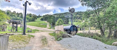 Ländliche Landschaft mit einem Schotterweg, der zu einer Holzhütte und einem großen zylindrischen Tank führt.