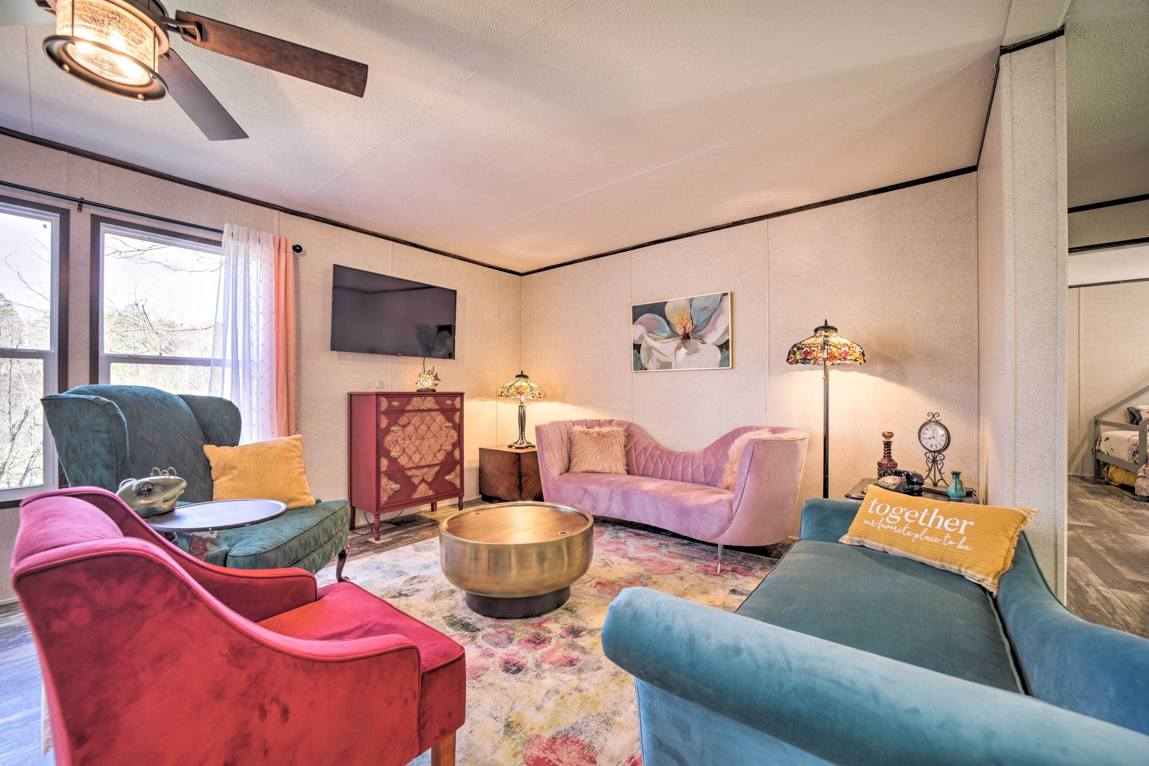 A living room with a round coffee table, two sofas, a television, and a ceiling fan.