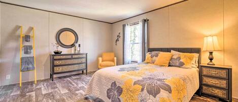A bedroom with a bed, dresser, chair, and nightstand.